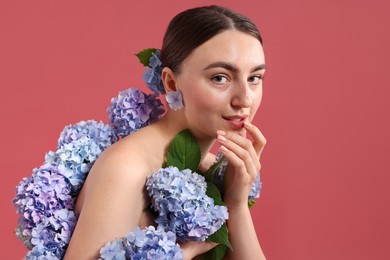 Photo of Beautiful young woman with hortensia flowers on color background