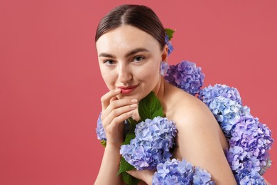 Photo of Beautiful young woman with hortensia flowers on color background