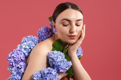 Photo of Beautiful young woman with hortensia flowers on color background
