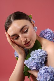 Photo of Beautiful young woman with hortensia flowers on color background