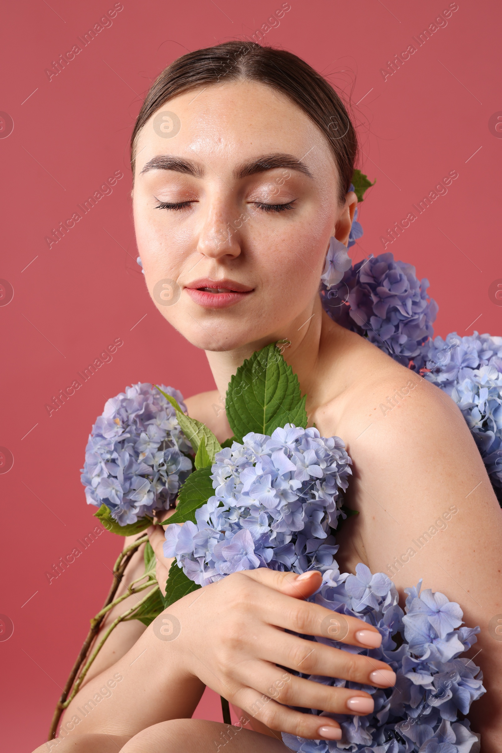 Photo of Beautiful young woman with hortensia flowers on color background