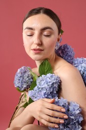 Photo of Beautiful young woman with hortensia flowers on color background
