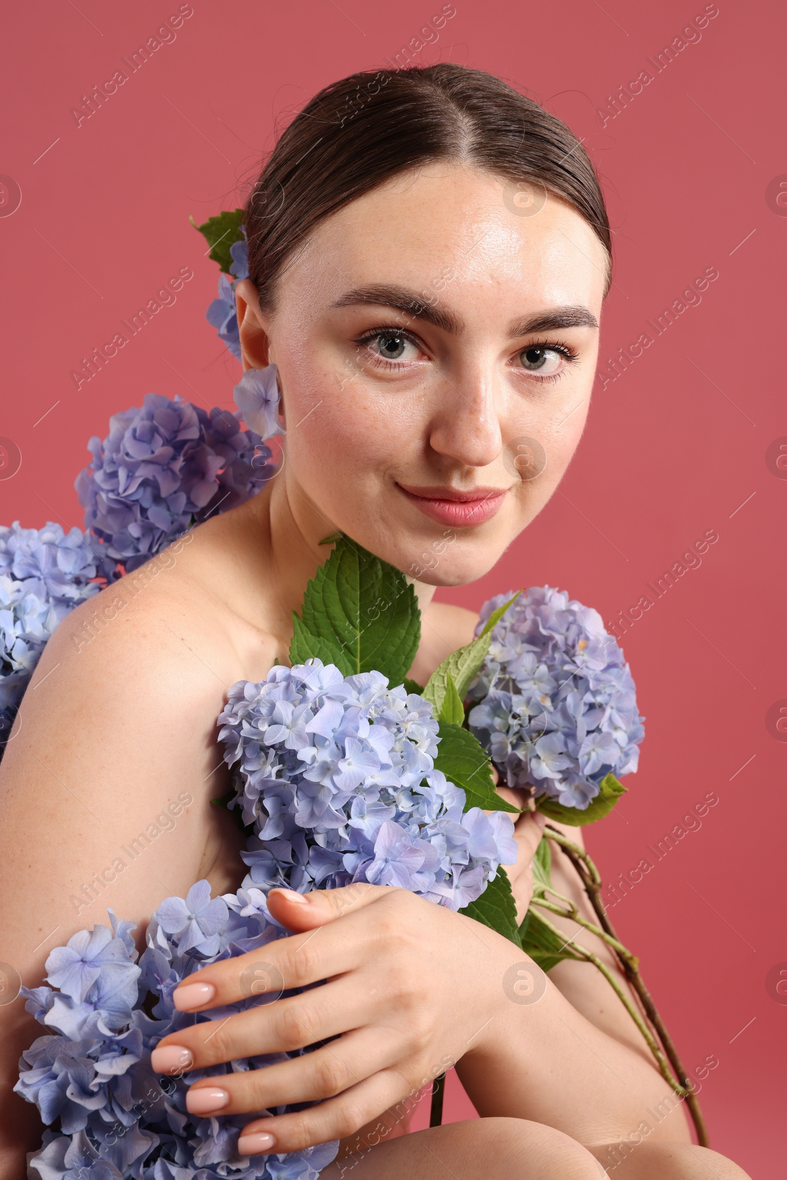 Photo of Beautiful young woman with hortensia flowers on color background
