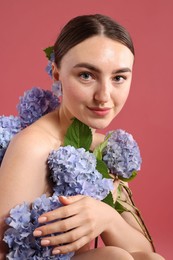 Photo of Beautiful young woman with hortensia flowers on color background