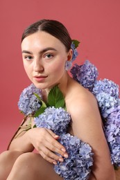 Photo of Beautiful young woman with hortensia flowers on color background