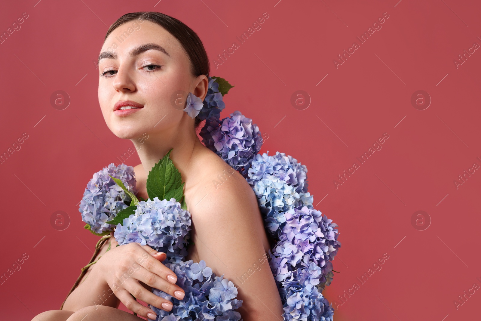 Photo of Beautiful young woman with hortensia flowers on color background. Space for text