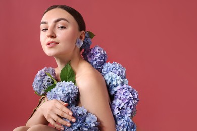 Photo of Beautiful young woman with hortensia flowers on color background. Space for text
