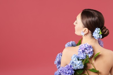 Photo of Beautiful young woman with hortensia flowers on color background, back view. Space for text