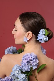 Photo of Beautiful young woman with hortensia flowers on color background, back view