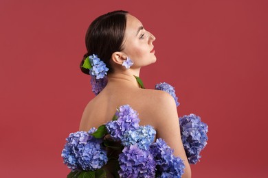 Photo of Beautiful young woman with hortensia flowers on color background