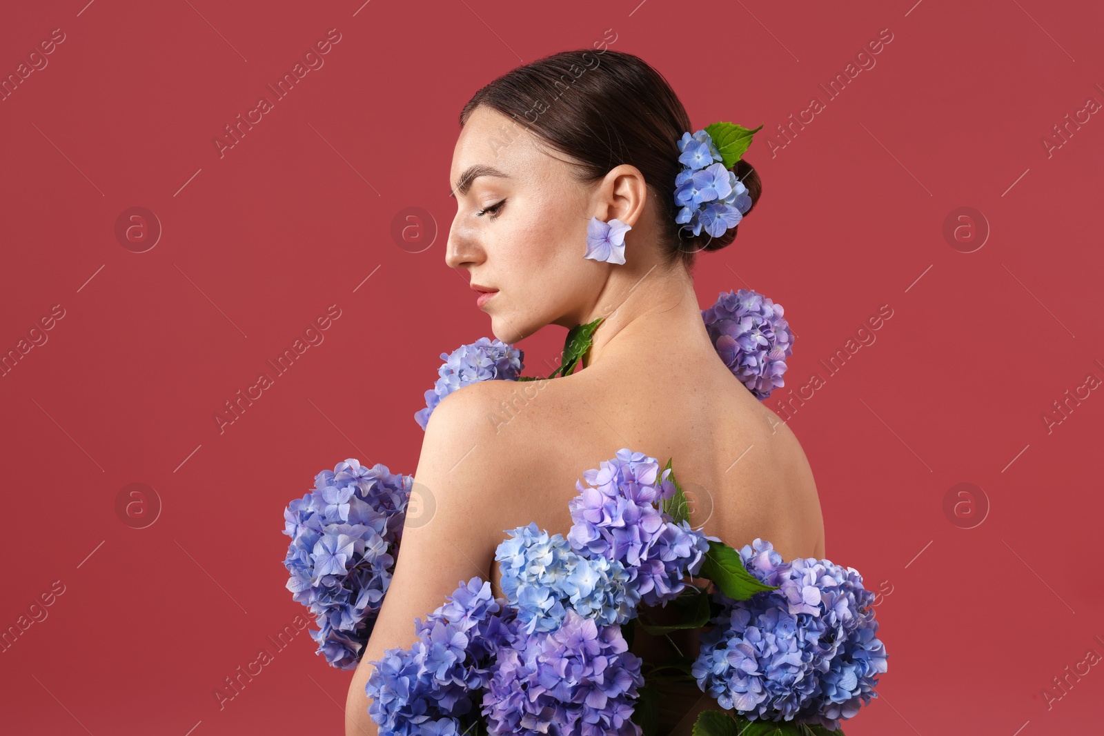 Photo of Beautiful young woman with hortensia flowers on color background