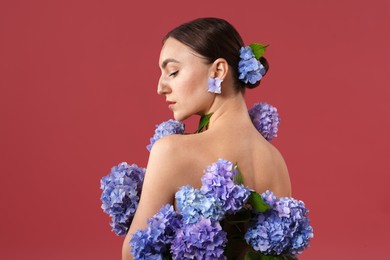 Photo of Beautiful young woman with hortensia flowers on color background
