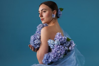 Photo of Portrait of beautiful woman with hortensia flowers on blue background