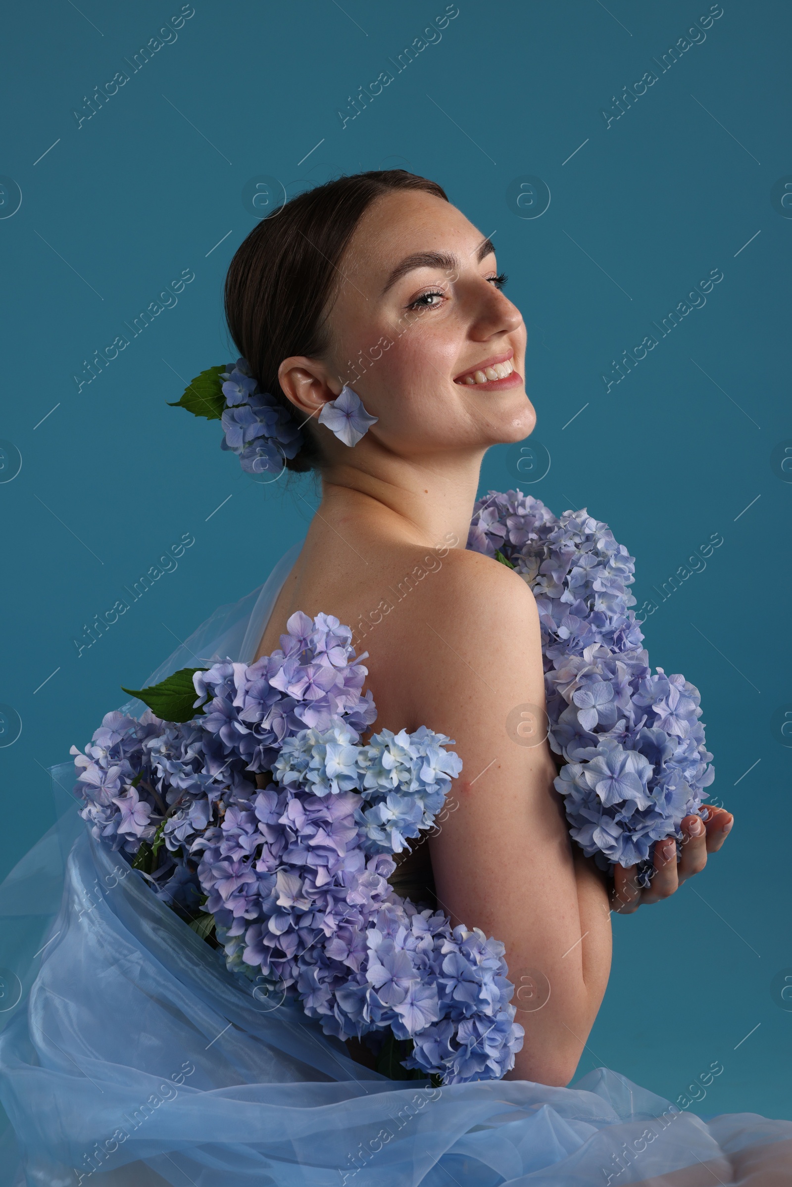Photo of Portrait of beautiful woman with hortensia flowers on blue background