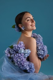 Photo of Portrait of beautiful woman with hortensia flowers on blue background