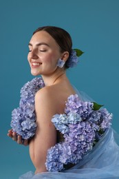Photo of Portrait of beautiful woman with hortensia flowers on blue background