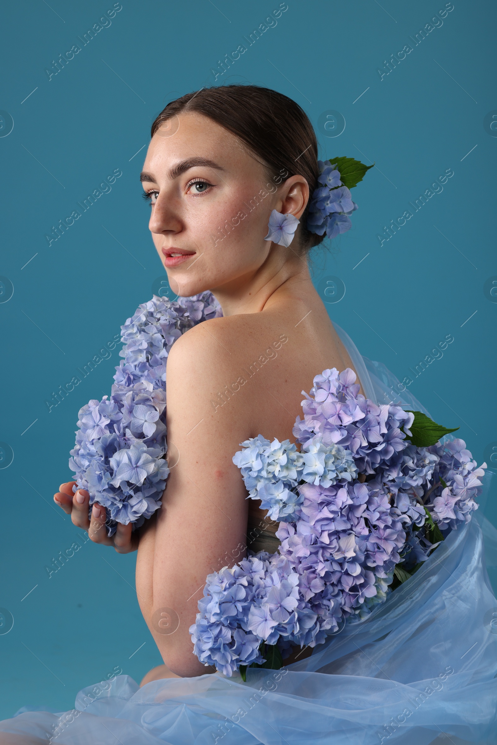Photo of Portrait of beautiful woman with hortensia flowers on blue background