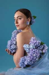 Photo of Portrait of beautiful woman with hortensia flowers on blue background