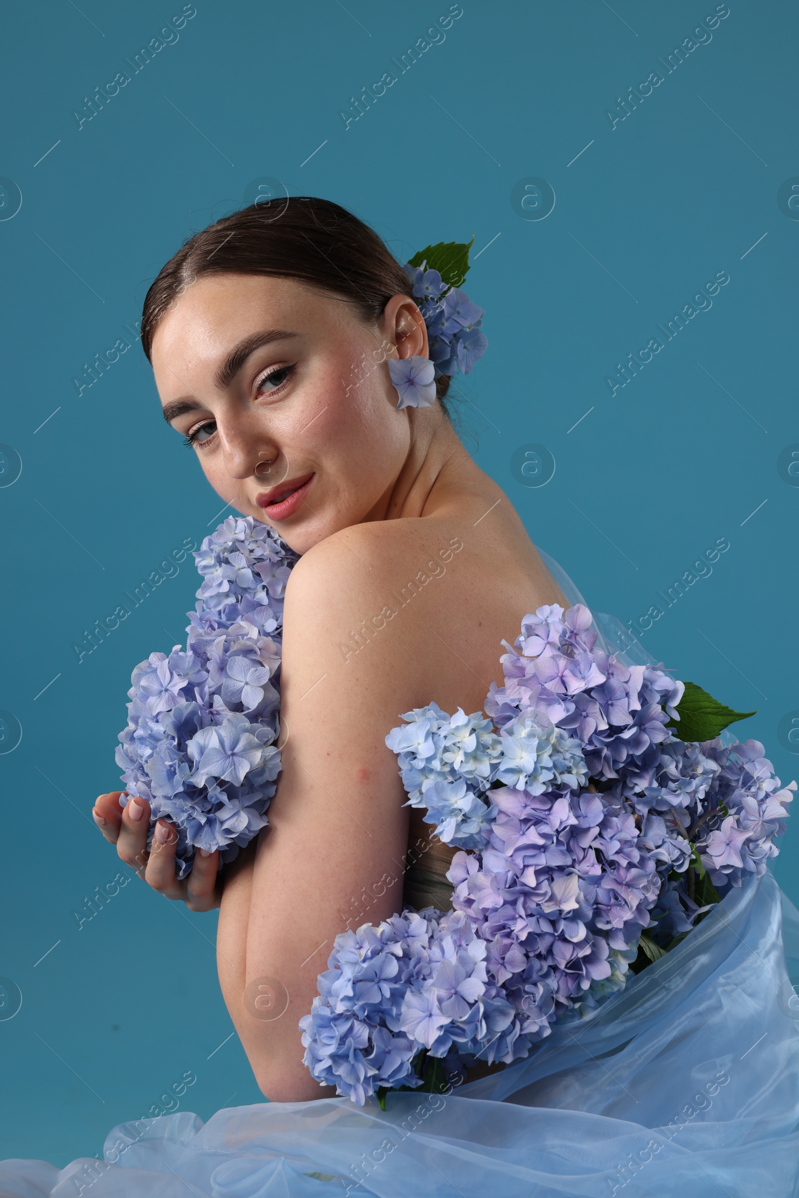 Photo of Portrait of beautiful woman with hortensia flowers on blue background
