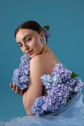 Photo of Portrait of beautiful woman with hortensia flowers on blue background