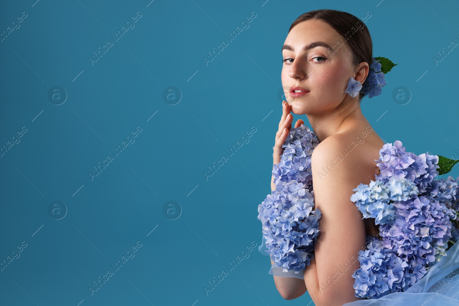Portrait of beautiful woman with hortensia flowers on blue background. Space for text Photo of Portrait of beautiful woman with hortensia flowers on blue background. Space for text