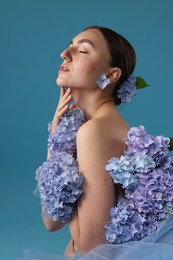 Photo of Portrait of beautiful woman with hortensia flowers on blue background