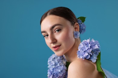 Photo of Beautiful young woman with hortensia flowers on blue background