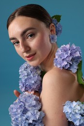 Photo of Beautiful young woman with hortensia flowers on blue background