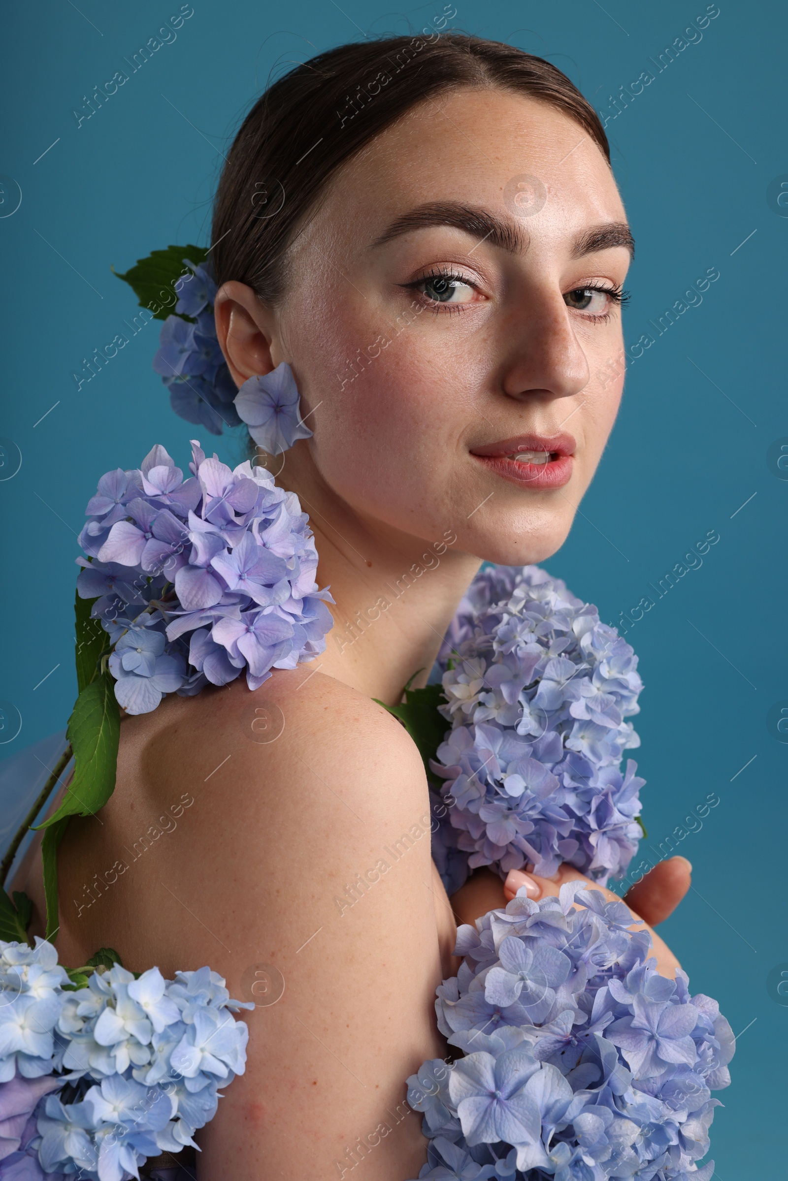 Beautiful young woman with hortensia flowers on blue background Photo of Beautiful young woman with hortensia flowers on blue background