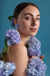 Photo of Beautiful young woman with hortensia flowers on blue background