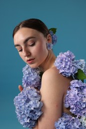 Photo of Beautiful young woman with hortensia flowers on blue background