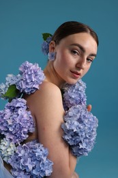 Photo of Beautiful young woman with hortensia flowers on blue background