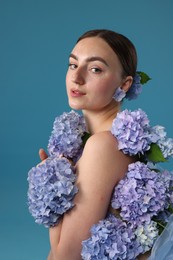 Photo of Beautiful young woman with hortensia flowers on blue background