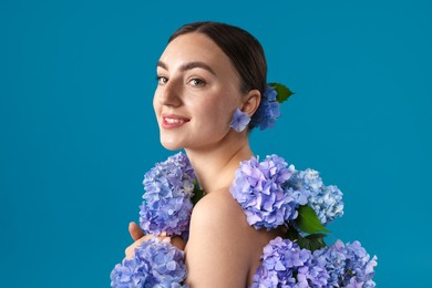 Photo of Beautiful young woman with hortensia flowers on blue background