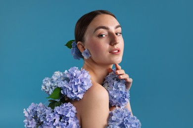 Photo of Beautiful young woman with hortensia flowers on blue background