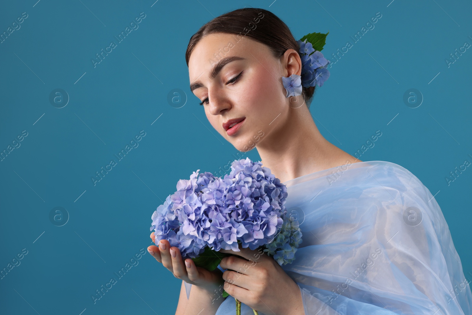 Portrait of beautiful woman with hortensia flowers and cloth on blue background Photo of Portrait of beautiful woman with hortensia flowers and cloth on blue background
