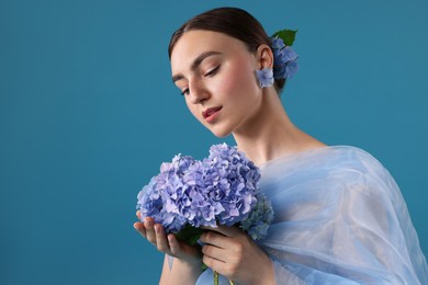 Photo of Portrait of beautiful woman with hortensia flowers and cloth on blue background