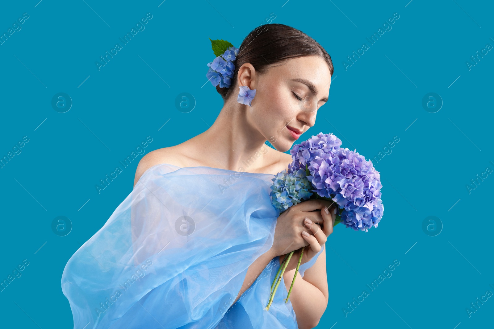 Photo of Portrait of beautiful woman with hortensia flowers and cloth on blue background