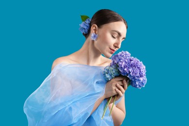 Photo of Portrait of beautiful woman with hortensia flowers and cloth on blue background