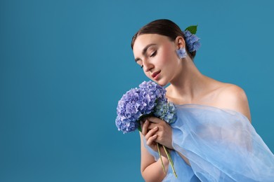 Photo of Portrait of beautiful woman with hortensia flowers and cloth on blue background. Space for text