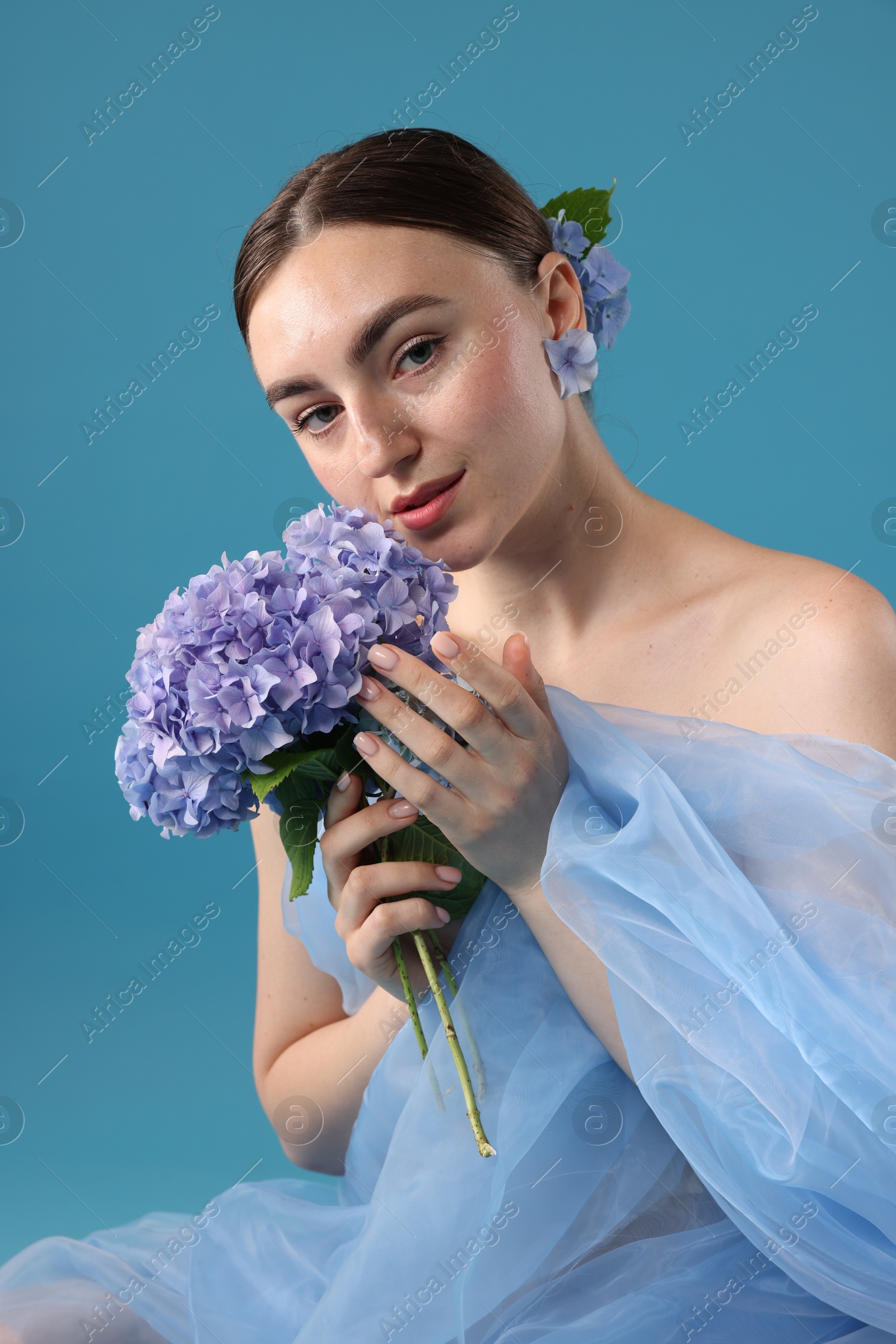 Photo of Portrait of beautiful woman with hortensia flowers and cloth on blue background