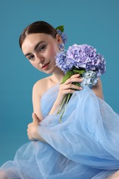 Photo of Portrait of beautiful woman with hortensia flowers and cloth on blue background