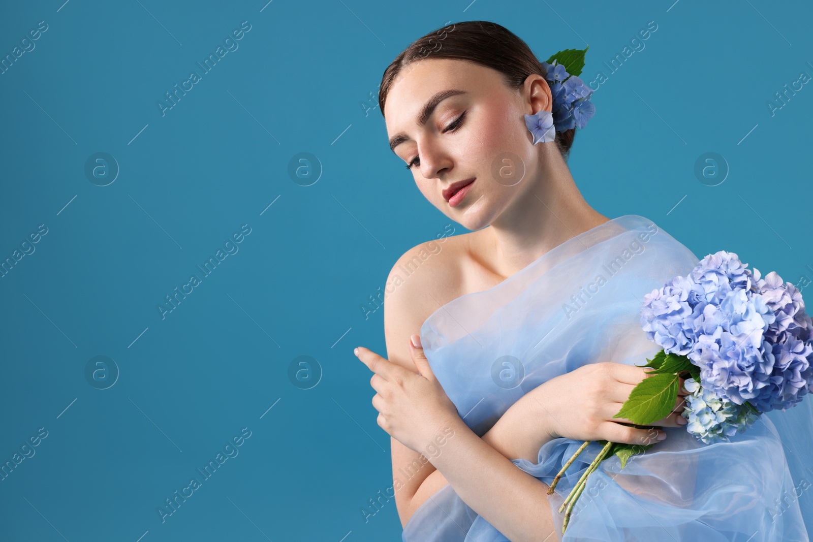 Photo of Portrait of beautiful woman with hortensia flowers and cloth on blue background. Space for text