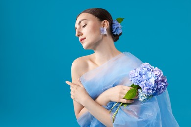 Photo of Portrait of beautiful woman with hortensia flowers and cloth on blue background