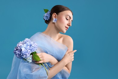 Photo of Portrait of beautiful woman with hortensia flowers and cloth on blue background. Space for text