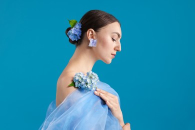 Photo of Portrait of beautiful woman with hortensia flowers and cloth on blue background. Space for text