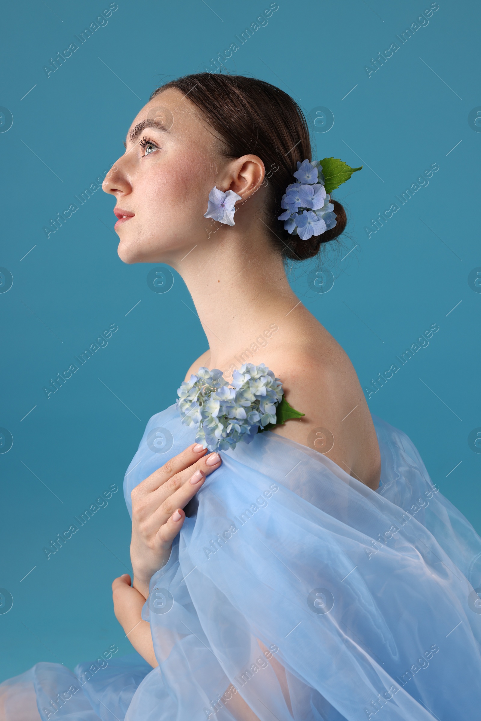 Portrait of beautiful woman with hortensia flowers and cloth on blue background Photo of Portrait of beautiful woman with hortensia flowers and cloth on blue background