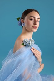 Photo of Portrait of beautiful woman with hortensia flowers and cloth on blue background