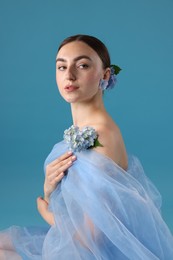Photo of Portrait of beautiful woman with hortensia flowers and cloth on blue background