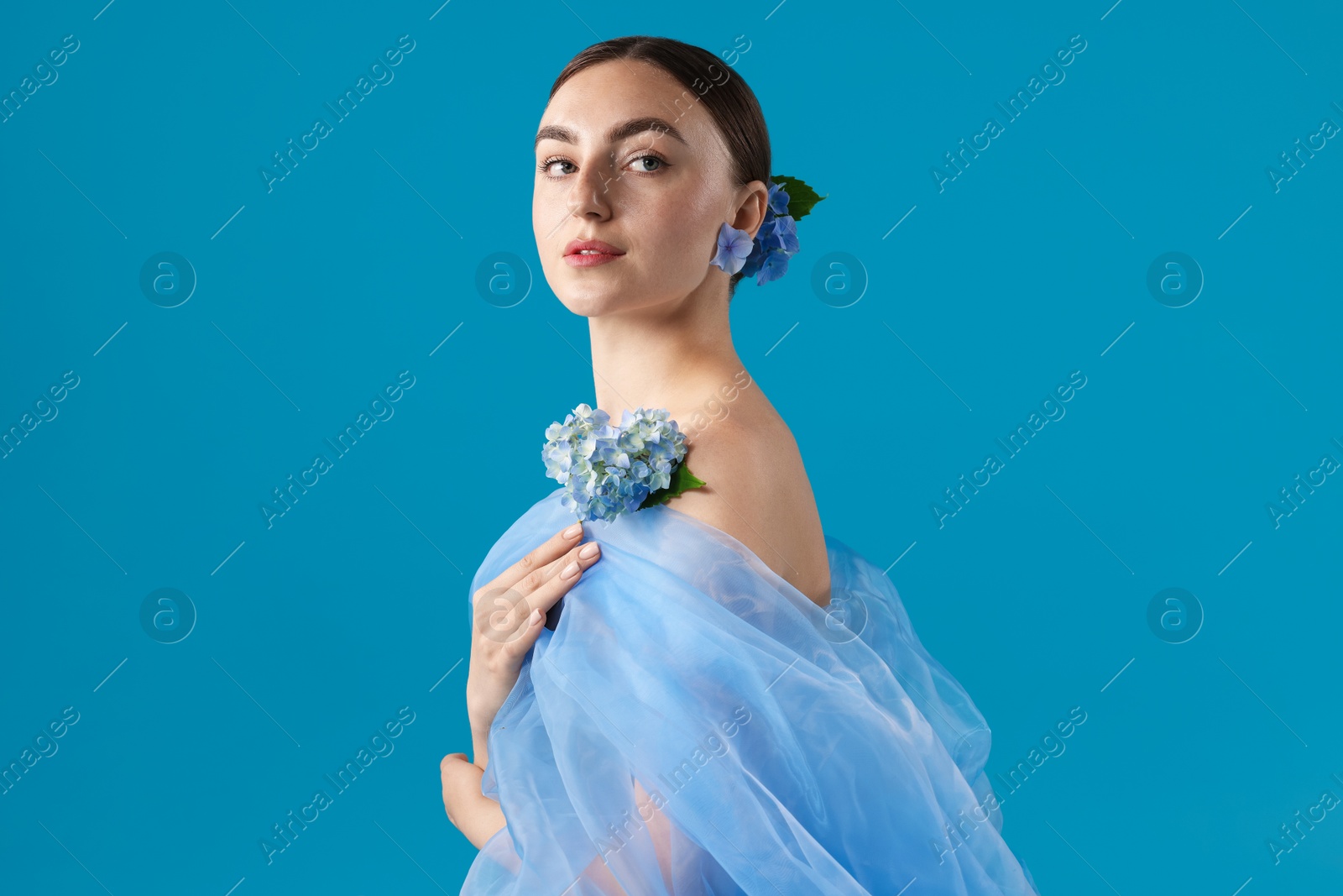Portrait of beautiful woman with hortensia flowers and cloth on blue background Photo of Portrait of beautiful woman with hortensia flowers and cloth on blue background
